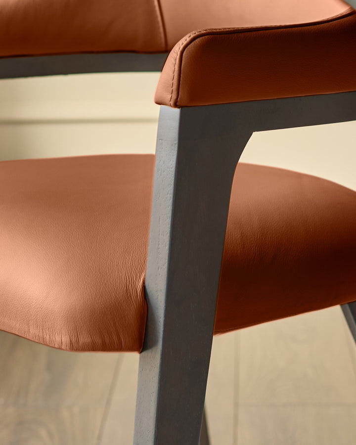 Dylan dining chair in tan leather, close-up of backrest and dark wooden leg frame.