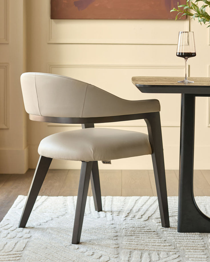 Dylan dining chair in natural leather with black wood frame, shown at an angle beside a small black table with wine glass.
