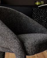 Easton dining chair in dark grey fabric, shown in close-up detail highlighting the textured weave and curved armrest design.
