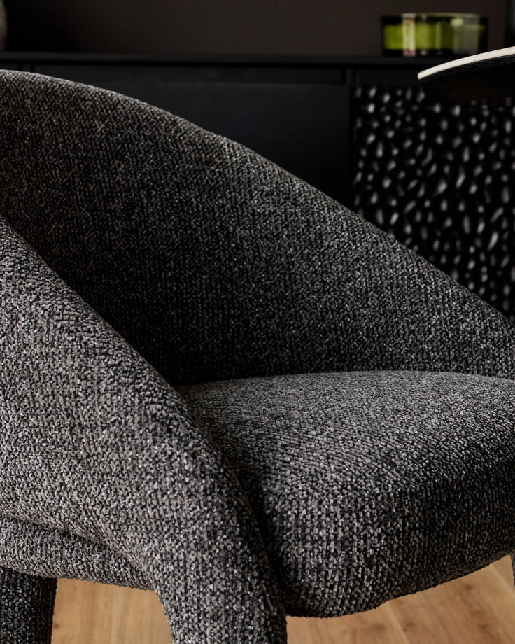 Easton dining chair in dark grey fabric, shown in close-up detail highlighting the textured weave and curved armrest design.