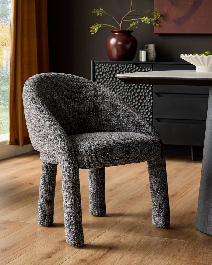 Easton dining chair in dark grey fabric with curved backrest and sturdy cylindrical legs, shown in modern interior setting.