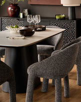 Easton dining chair in dark grey fabric with rounded back and sturdy legs, shown at dining table.