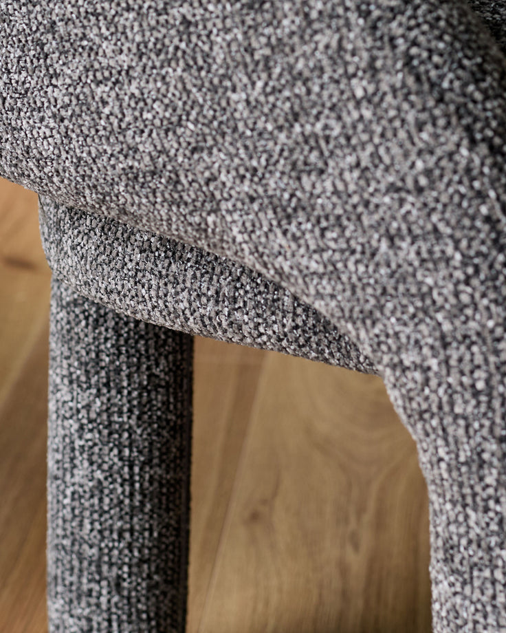 Easton dining bench in dark grey fabric, close-up detail of textured upholstery and wooden leg.