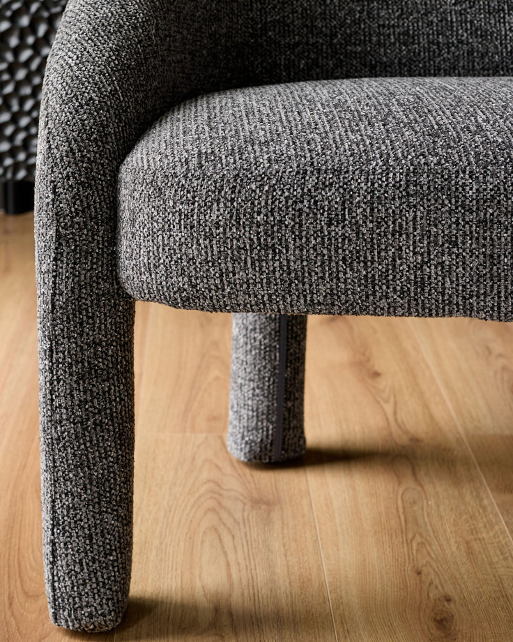 Dark grey fabric dining bench with rounded cylindrical legs, shown from a side angle on wooden flooring.