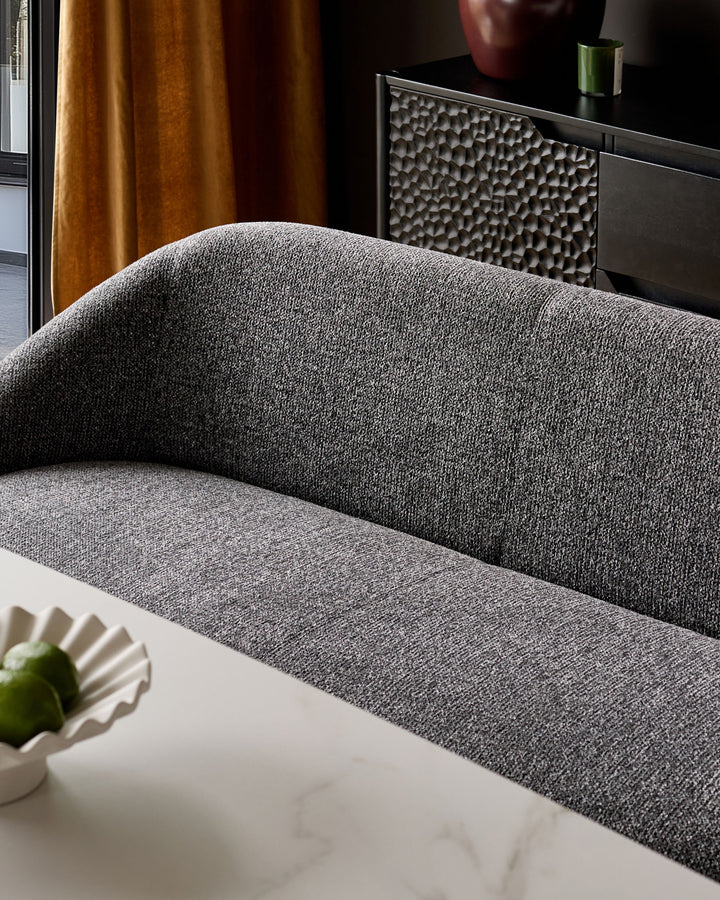 Easton dining bench in dark grey fabric, curved backrest, white base, angled side view.