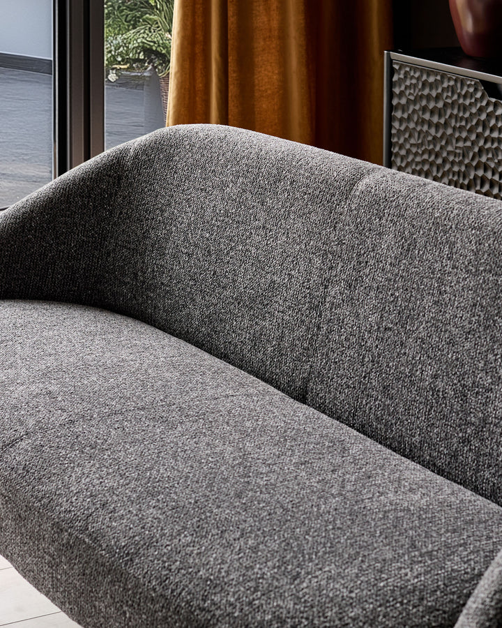 Easton dining bench in dark grey fabric, showing curved backrest and seat cushion detail in modern interior setting.