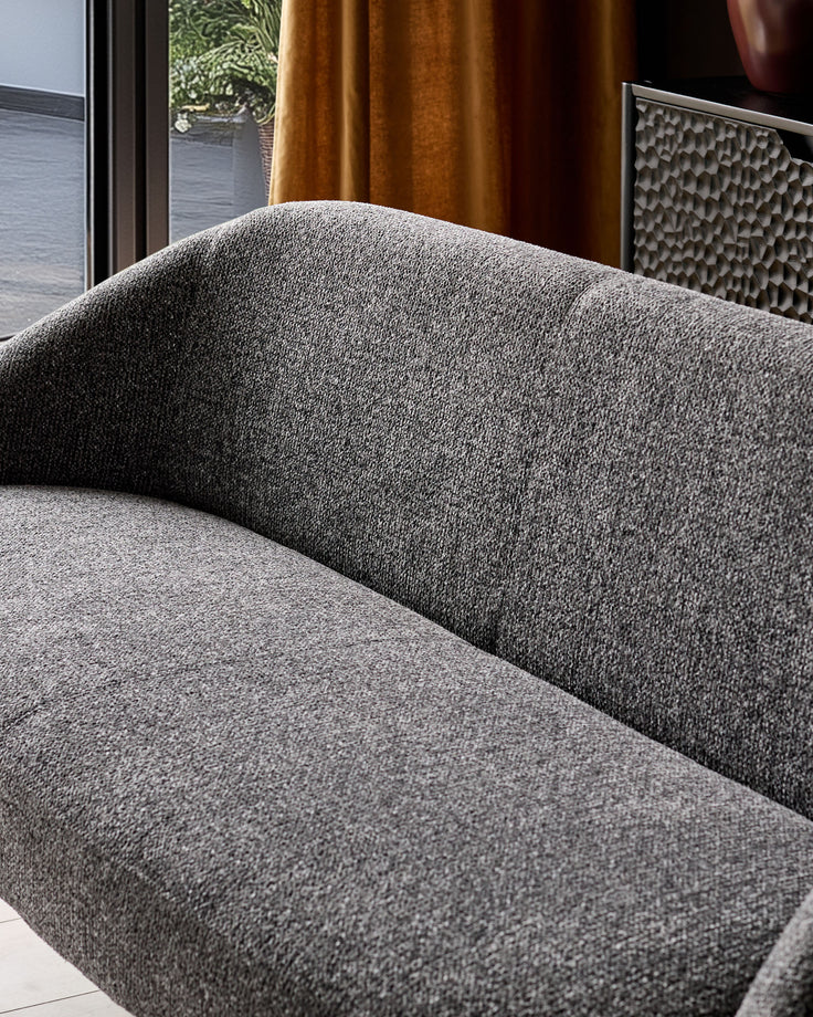 Easton dining bench in dark grey fabric, showing curved backrest and seat cushion detail in modern interior setting.
