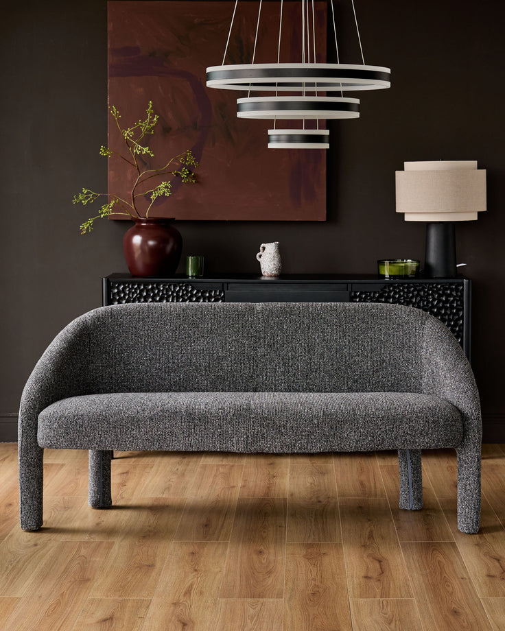 Easton dining bench in dark grey fabric with curved back and four upholstered legs, shown in styled room setting.