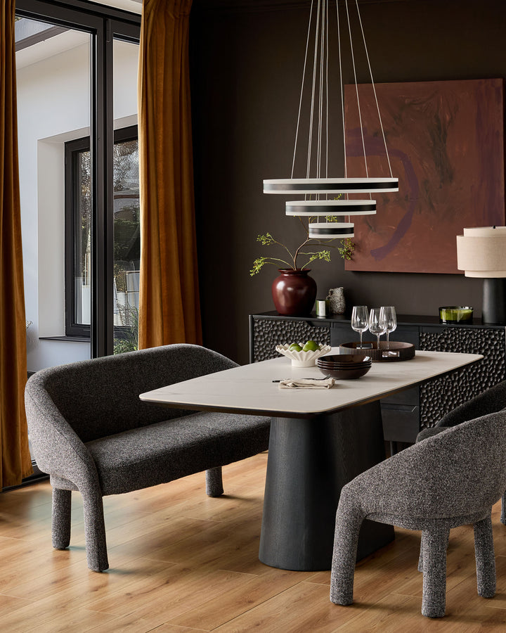 Easton dining bench in dark grey fabric, curved backrest, shown in modern dining room setting with table and chairs.