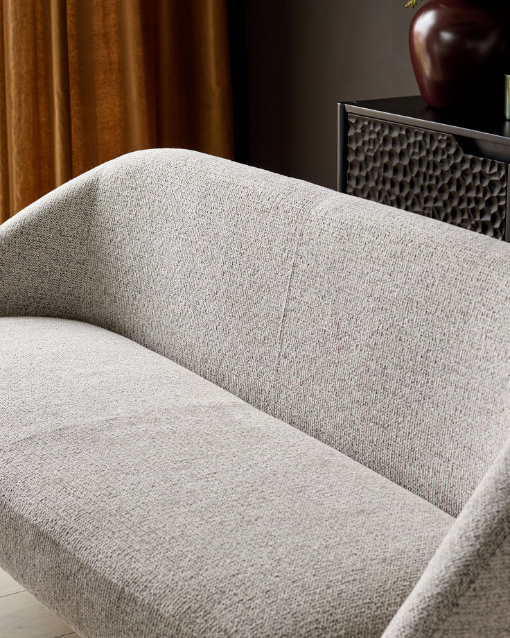 Easton dining bench in light grey fabric, showing curved backrest and seat from a close-up side angle.