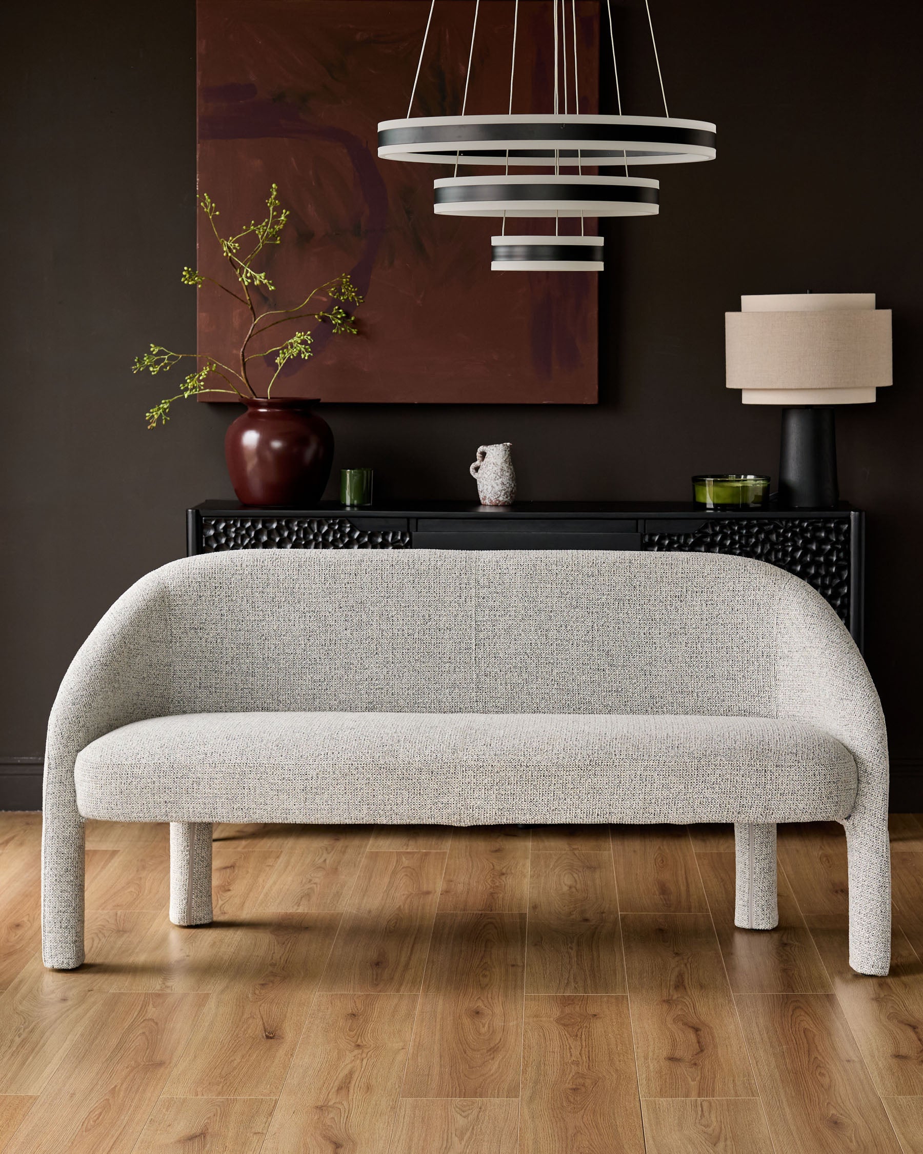 Easton dining bench in light grey fabric with curved back and armless design, shown in modern interior setting.