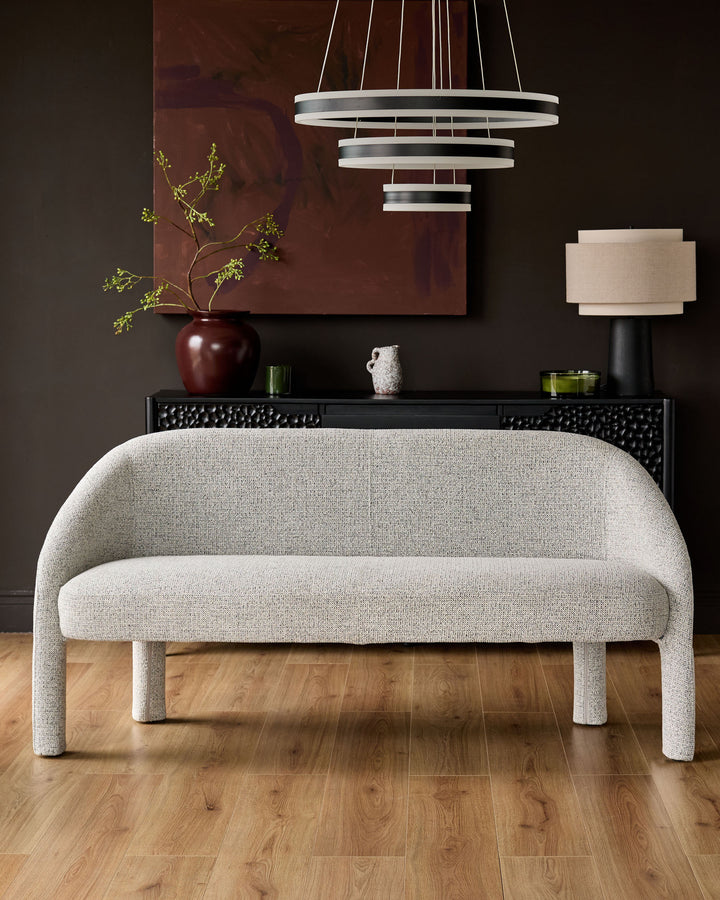 Easton dining bench in light grey fabric with curved back and armless design, shown in modern interior setting.