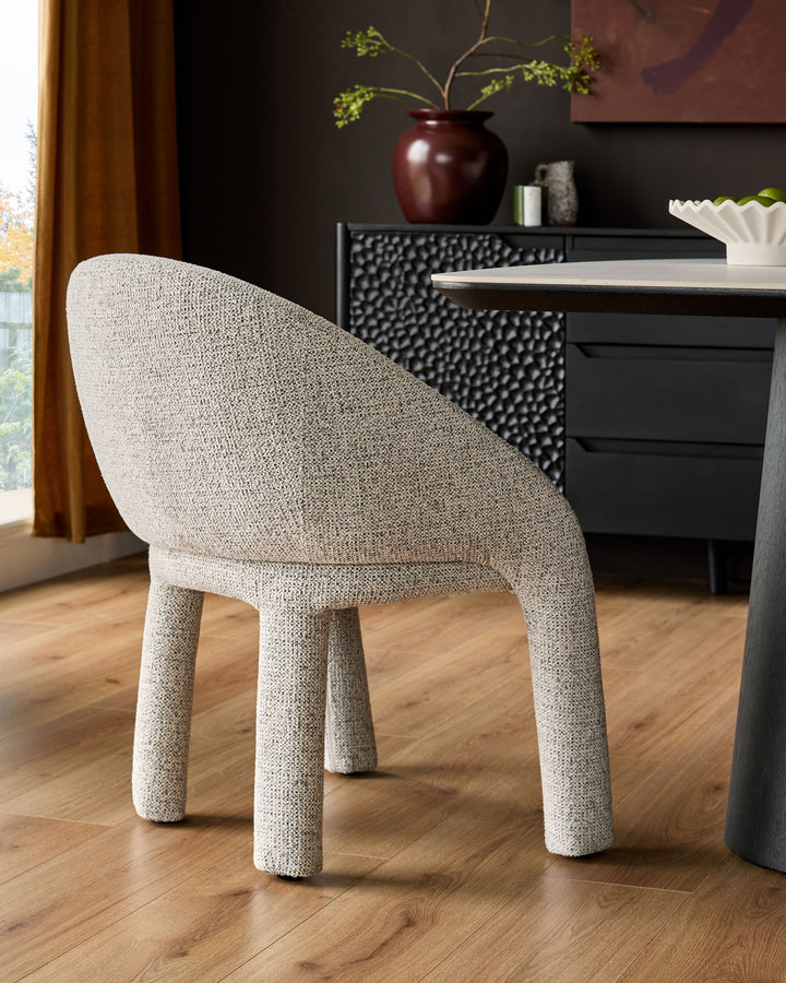 Easton dining chair in light grey fabric, shown from rear angle with curved backrest and cylindrical legs on wooden floor.