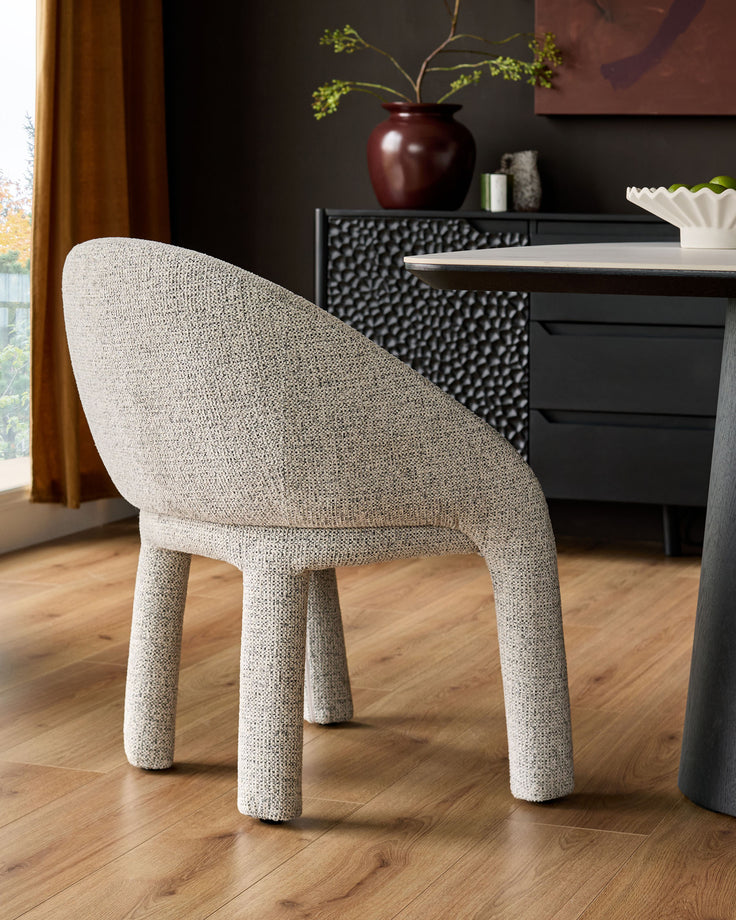Easton dining chair in light grey fabric, shown from rear angle with curved backrest and cylindrical legs on wooden floor.
