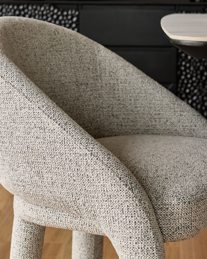 Easton dining chair in light grey fabric, close-up detail of curved backrest and upholstered seat.