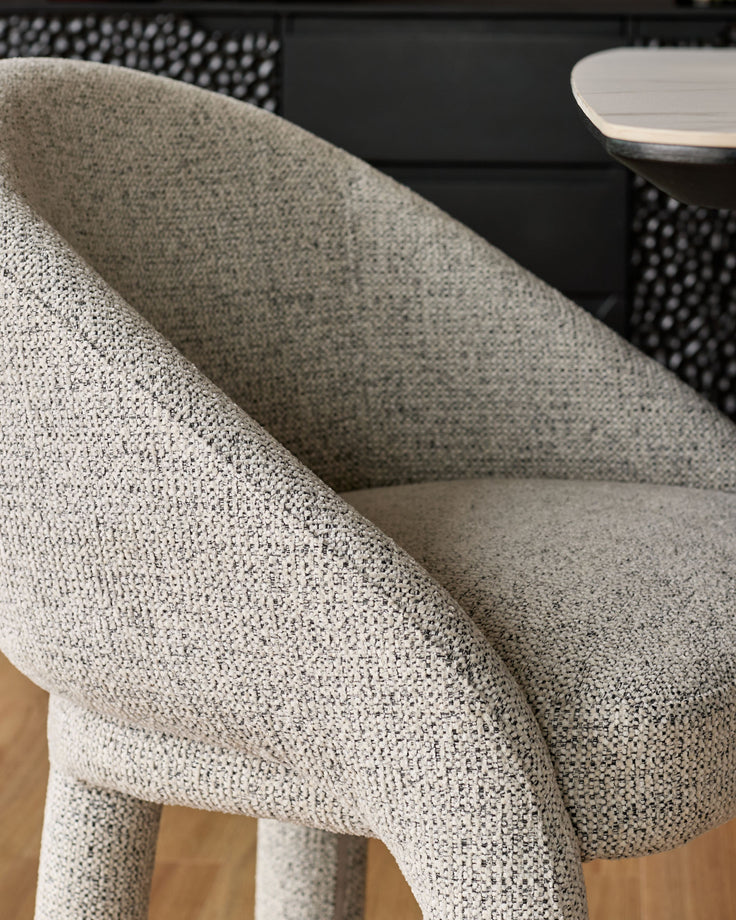 Easton dining chair in light grey fabric, close-up detail of curved backrest and upholstered seat.