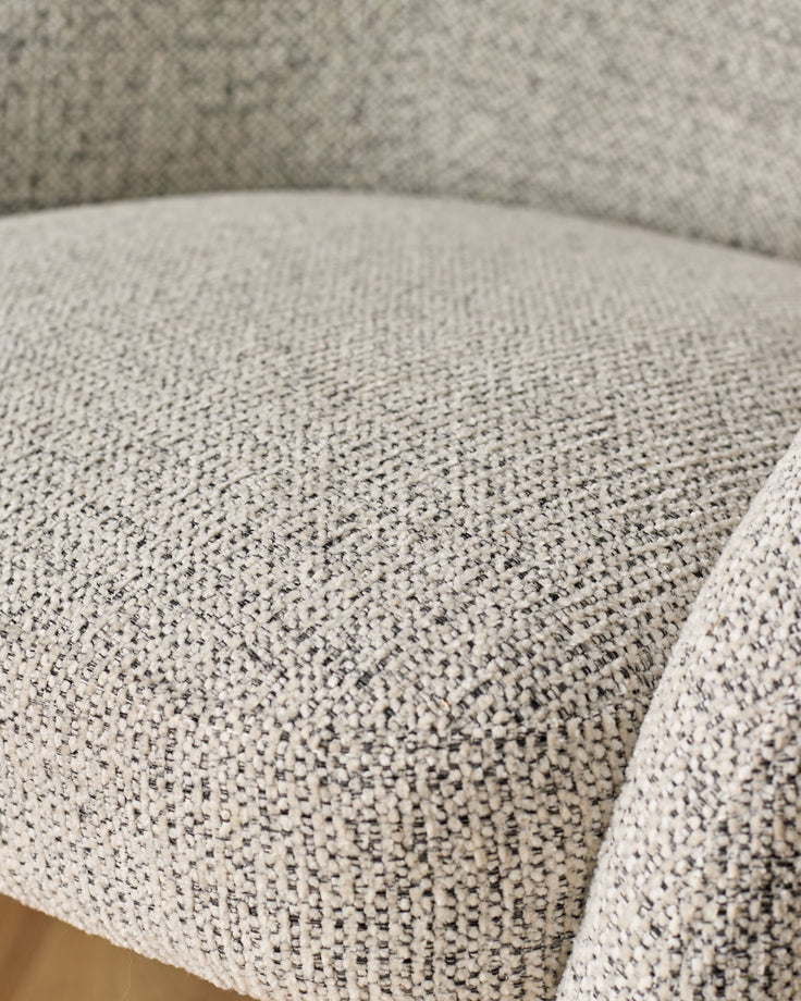 Close-up of light grey upholstered dining chair seat showing woven fabric texture and curved edge detail.