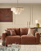 Eden two-seater sofa in apricot fabric, displayed in a styled living room setting with decorative pillows and accessories.