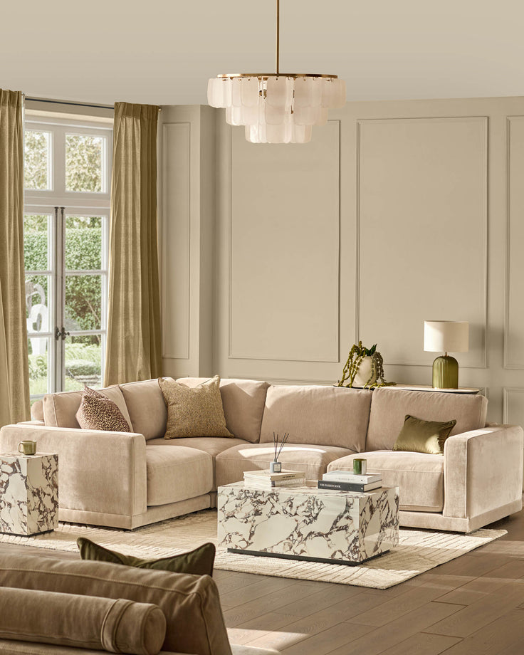 Eden small corner sofa in champagne fabric, styled in a bright living room with coordinating pillows and marble coffee table.