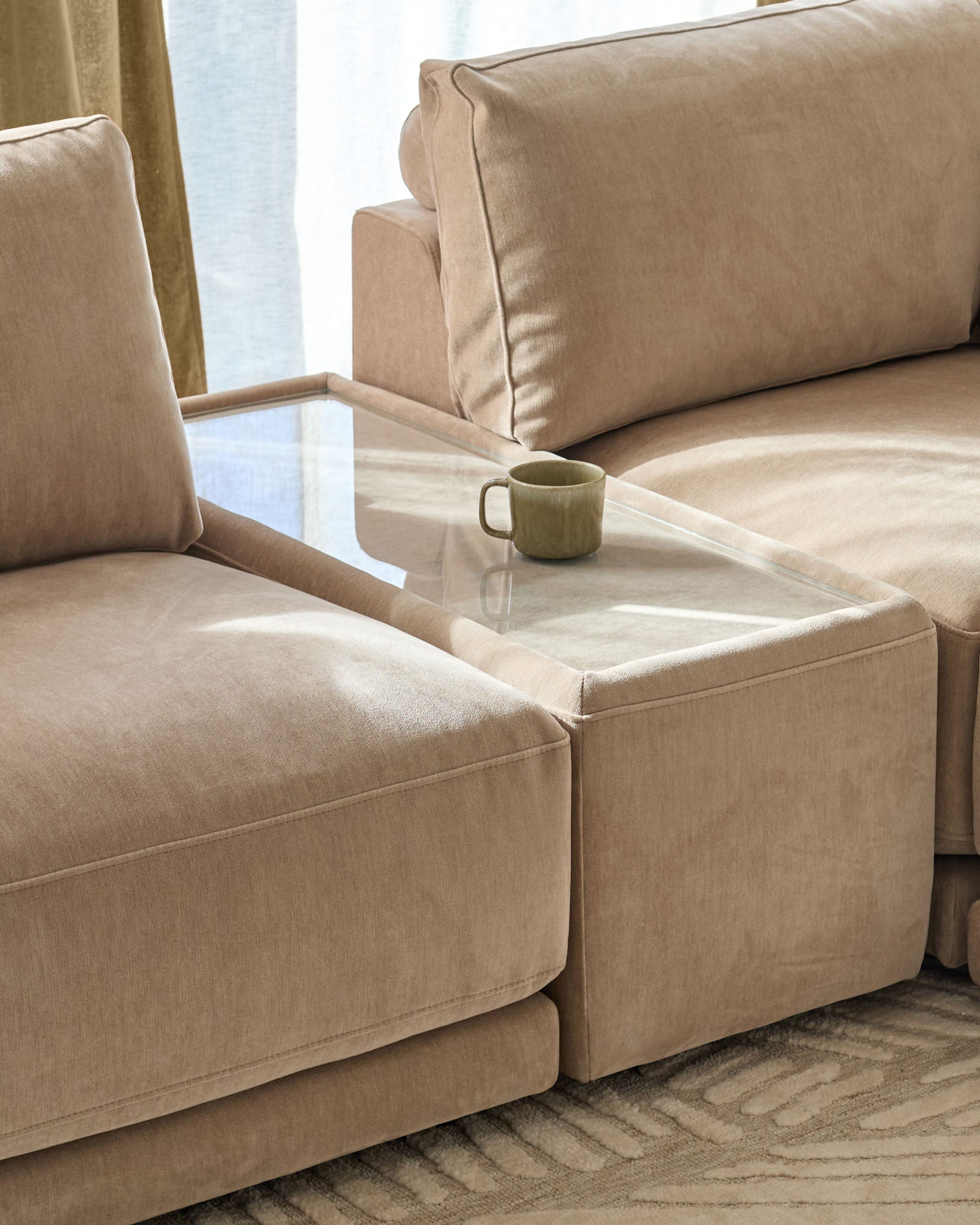 Eden side table module with glass top and champagne fabric base, positioned between two beige upholstered seating sections.