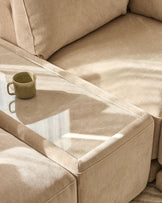 Eden side table module in champagne fabric with glass top, positioned between beige upholstered chairs with warm sunlight.