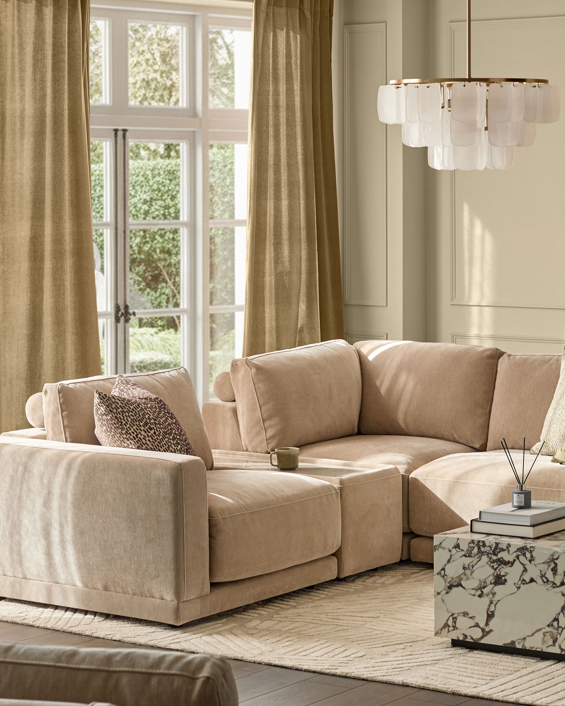 Eden side table module in champagne fabric with glass top, shown in living room setting with beige sectional sofa.