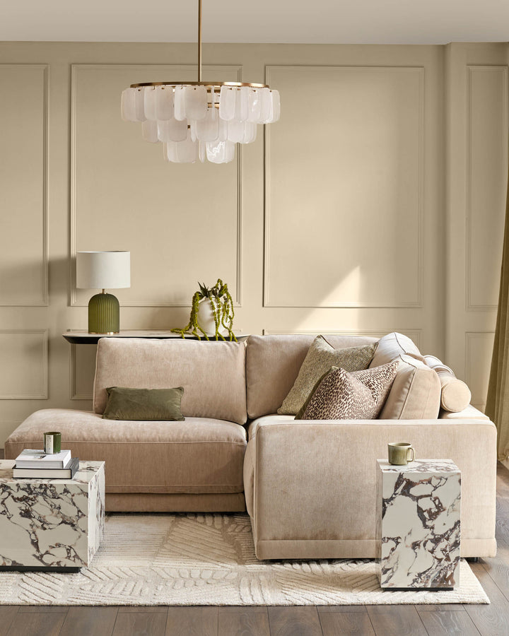 Champagne fabric sectional sofa with left-facing chaise, displayed in a styled living room setting with coordinating pillows and brass pendant light above.