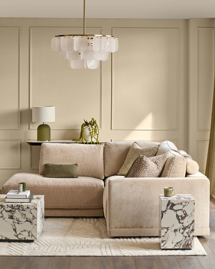 Champagne fabric sectional sofa with left-facing chaise, displayed in a styled living room setting with coordinating pillows and brass pendant light above.