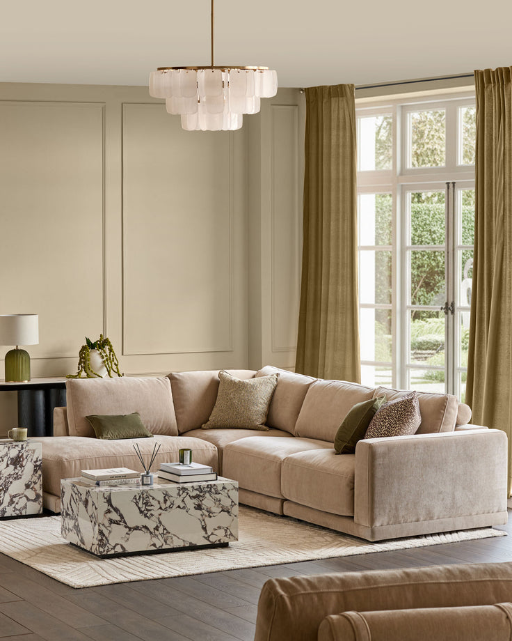 Champagne upholstered sectional sofa with left-facing chaise, shown in styled living room setting with neutral décor.