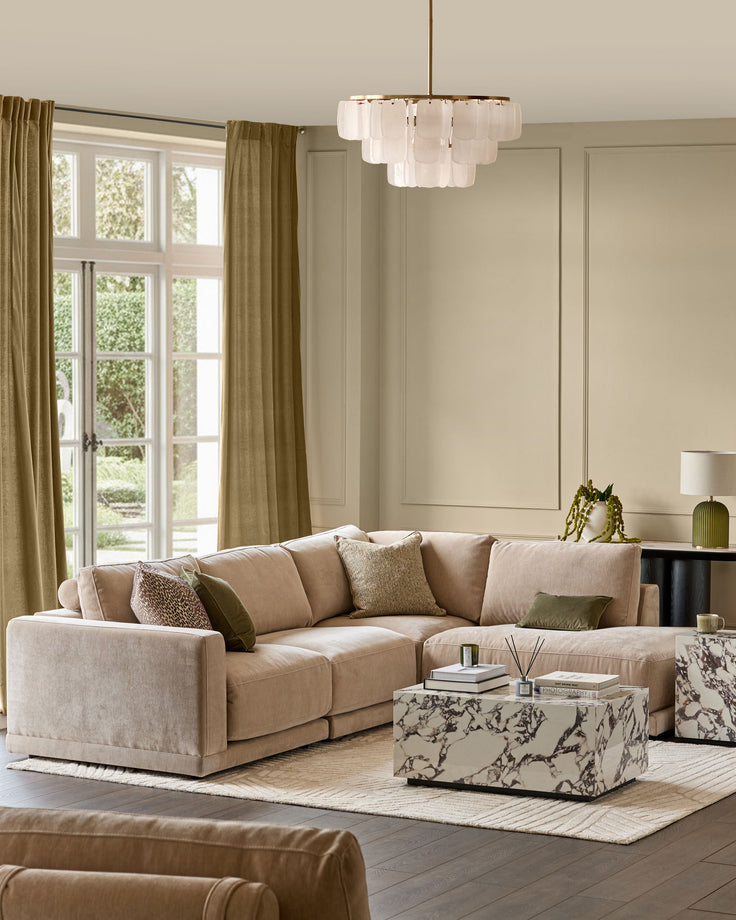 Eden Right Large Chaise Sofa in champagne fabric, styled in a bright living room with matching pillows and patterned ottoman.