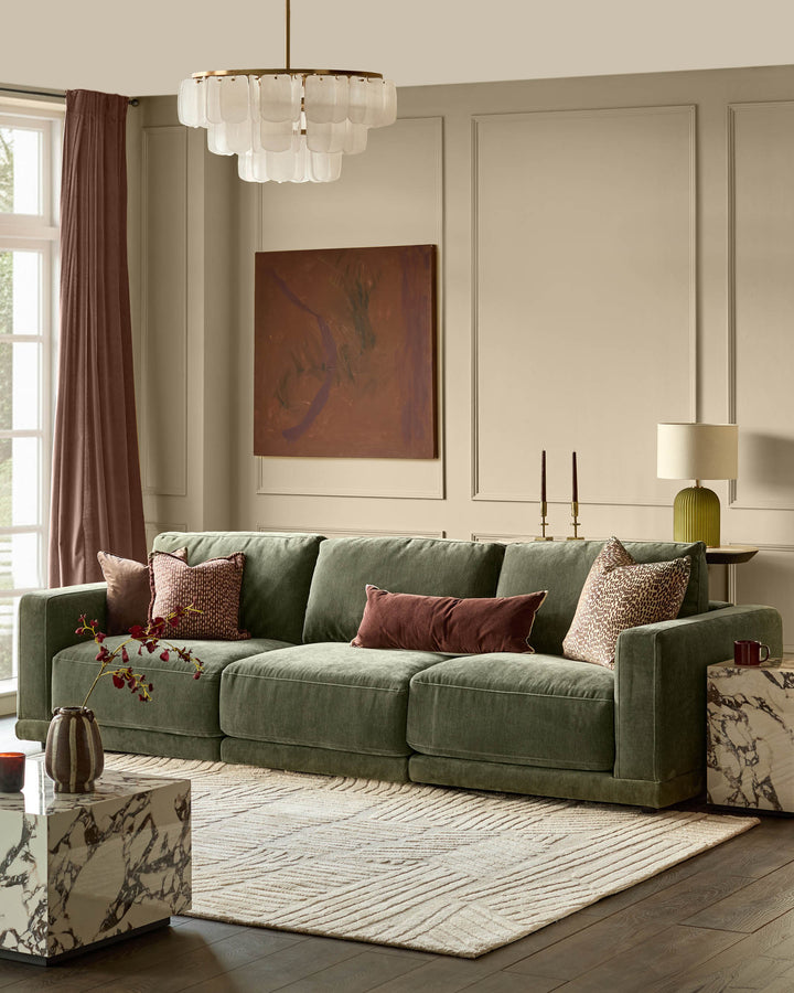 Eden 3-seater sofa in dark green fabric, displayed in a bright living room with decorative pillows and neutral décor.