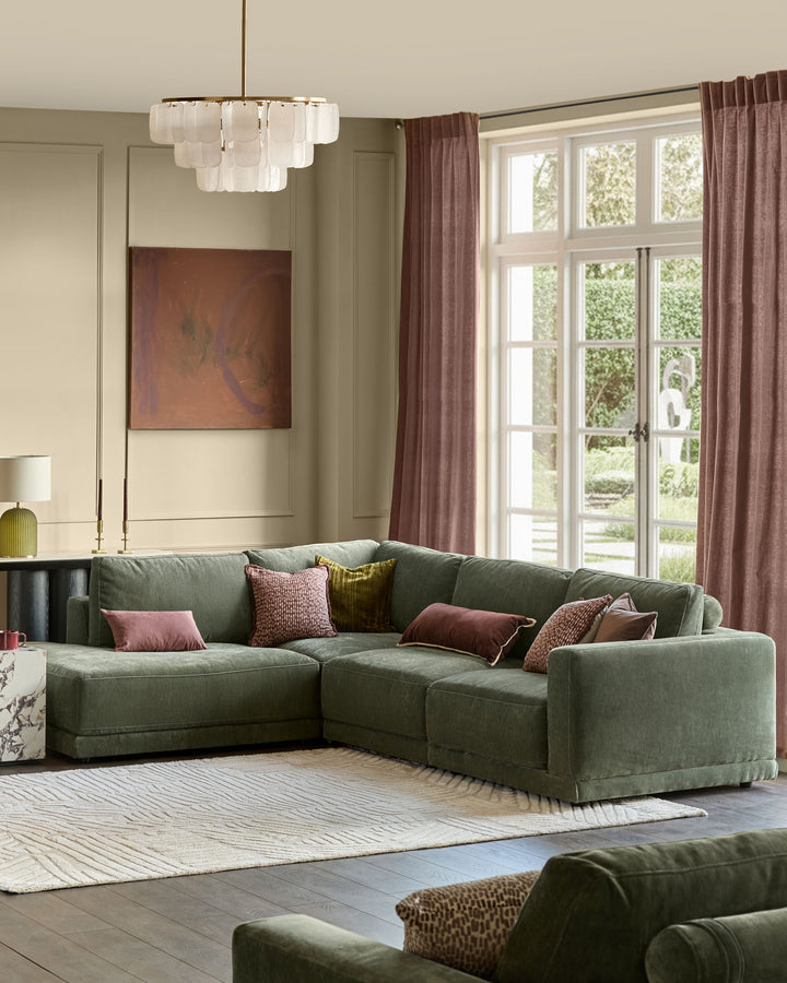 Eden left large chaise sofa in dark green fabric, displayed in a bright living room with decorative pillows.
