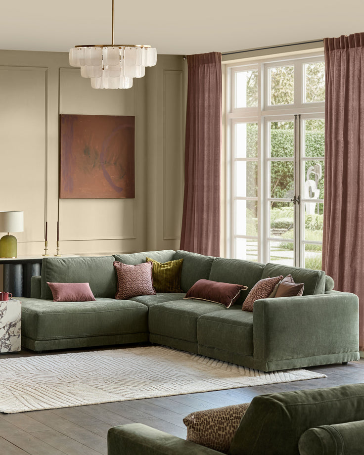 Eden left large chaise sofa in dark green fabric, displayed in a bright living room with decorative pillows.