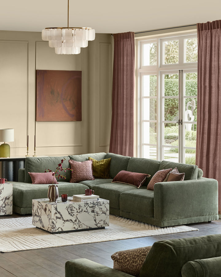 Eden left large chaise sofa in dark green fabric, displayed in a bright living room setting with decorative pillows.