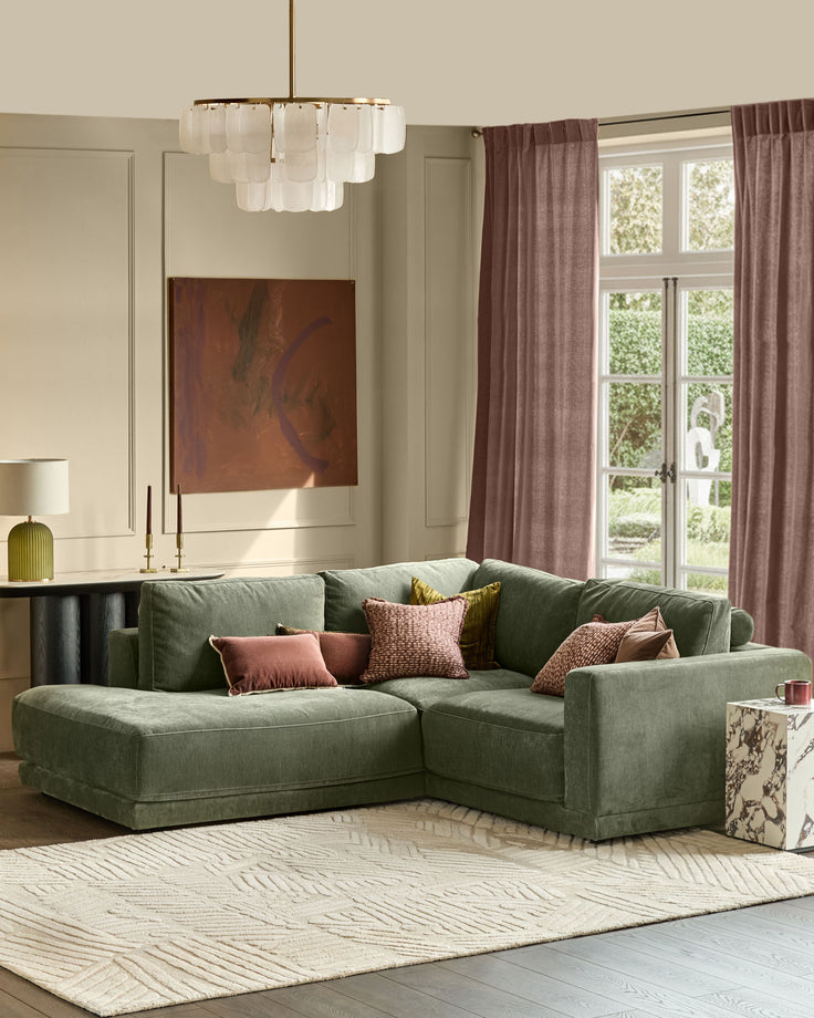 Dark green left-facing sectional sofa with chaise lounge, rounded arms, and textured upholstery in modern living room setting.