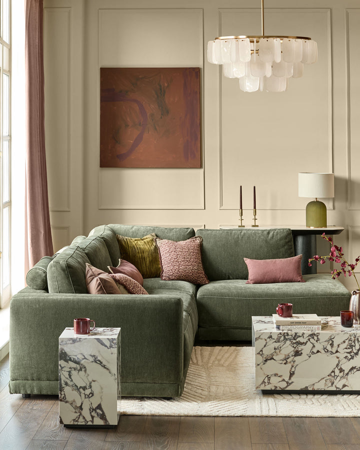 Dark green fabric right-facing large chaise sectional sofa with rolled arms and multiple decorative pillows in a styled living room.