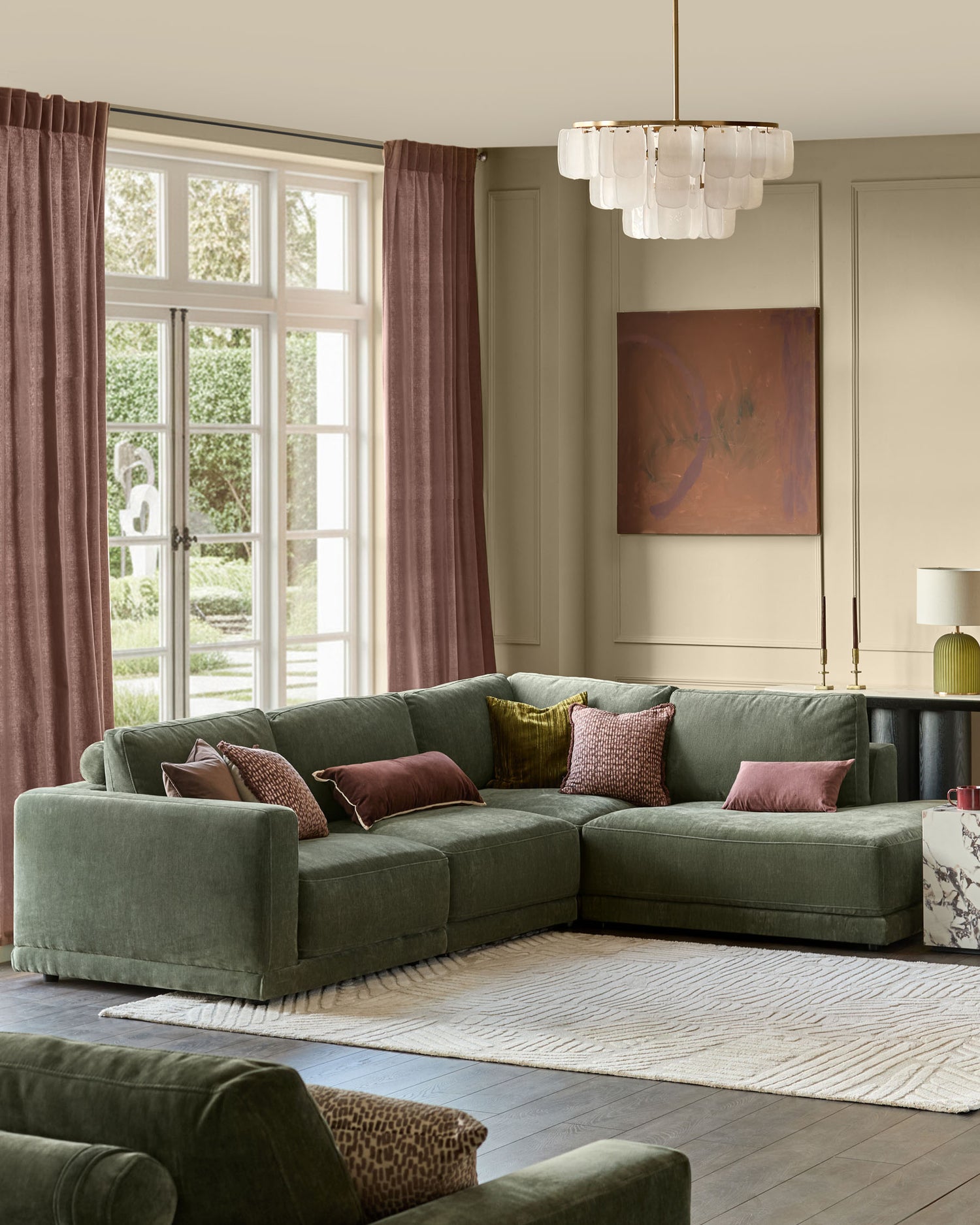 Dark green fabric sectional sofa with right chaise, displayed in a bright living room with mauve curtains and modern decor.
