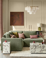 Dark green upholstered right-facing chaise sectional sofa with rolled arms and multiple decorative pillows in a styled living room.