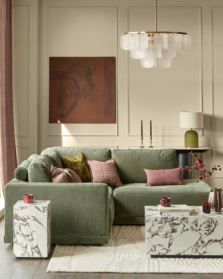 Dark green upholstered right-facing chaise sectional sofa with rolled arms and multiple decorative pillows in a styled living room.