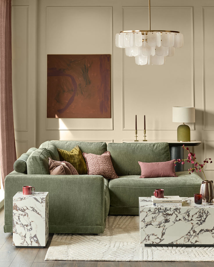 Dark green upholstered right-facing chaise sectional sofa with rolled arms and multiple decorative pillows in a styled living room.