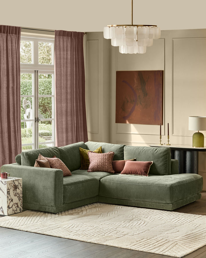 Dark green fabric right-facing sectional sofa with chaise lounge, displayed in a bright living room setting.