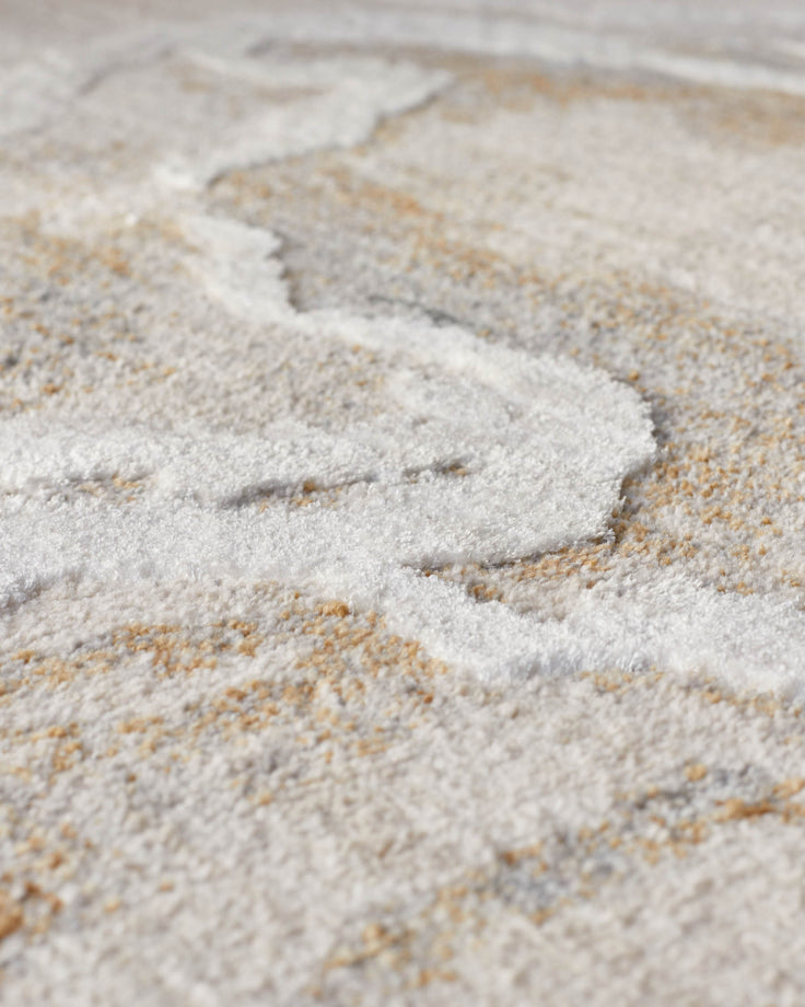 Textured neutral coloured rug with a subtle, wavy pattern in white and beige. Close-up shot showing the rug's soft texture.