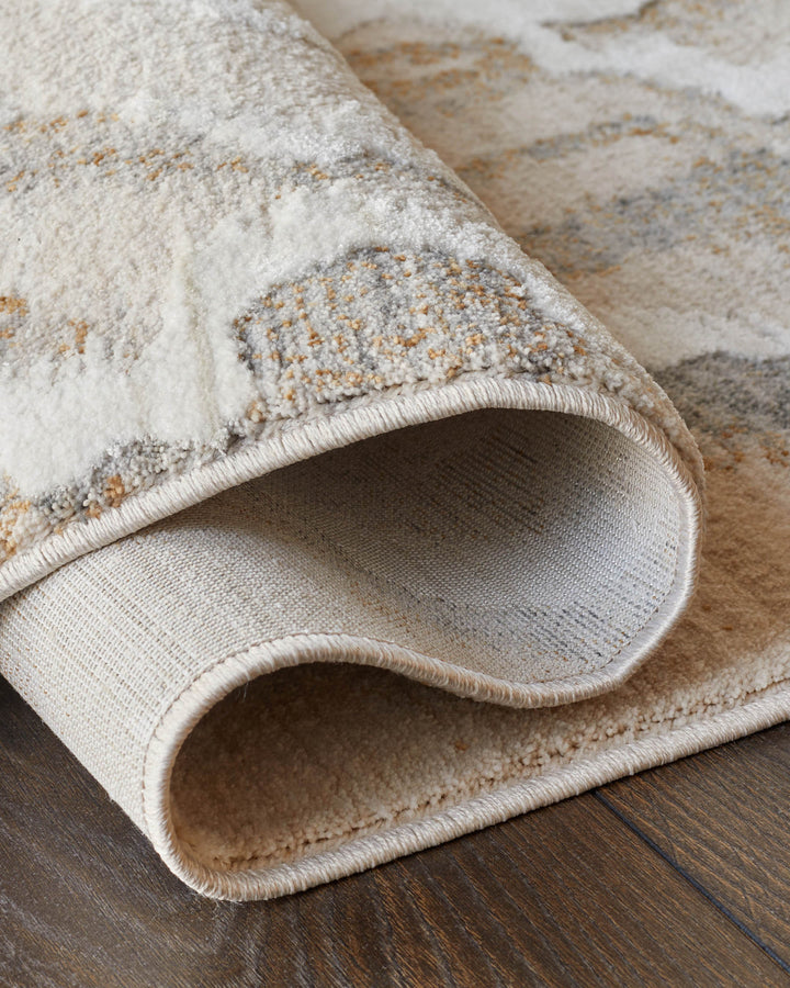 Rolled up rug with abstract patterns, cream and grey, on a dark wooden floor. High quality rug texture.