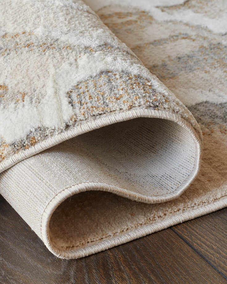 Rolled up rug with abstract patterns, cream and grey, on a dark wooden floor. High quality rug texture.