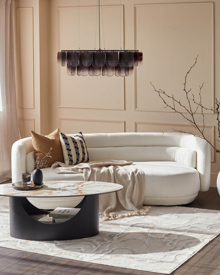 Stylish living room featuring a white sofa, marble coffee table, and a modern chandelier, exuding elegance and comfort.