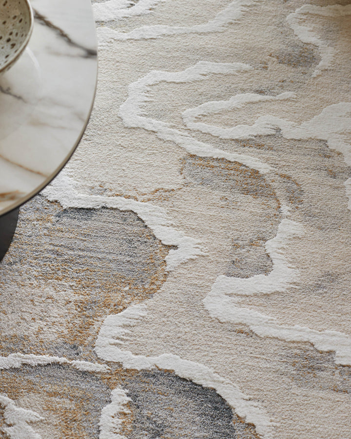 A marble-topped coffee table sits atop a patterned rug in neutral tones with grey and gold accents.