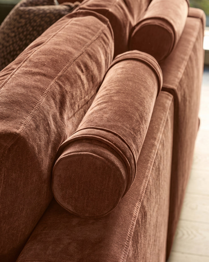 Eden 2-seater sofa in apricot fabric, close-up of rolled arm detail and stitching.