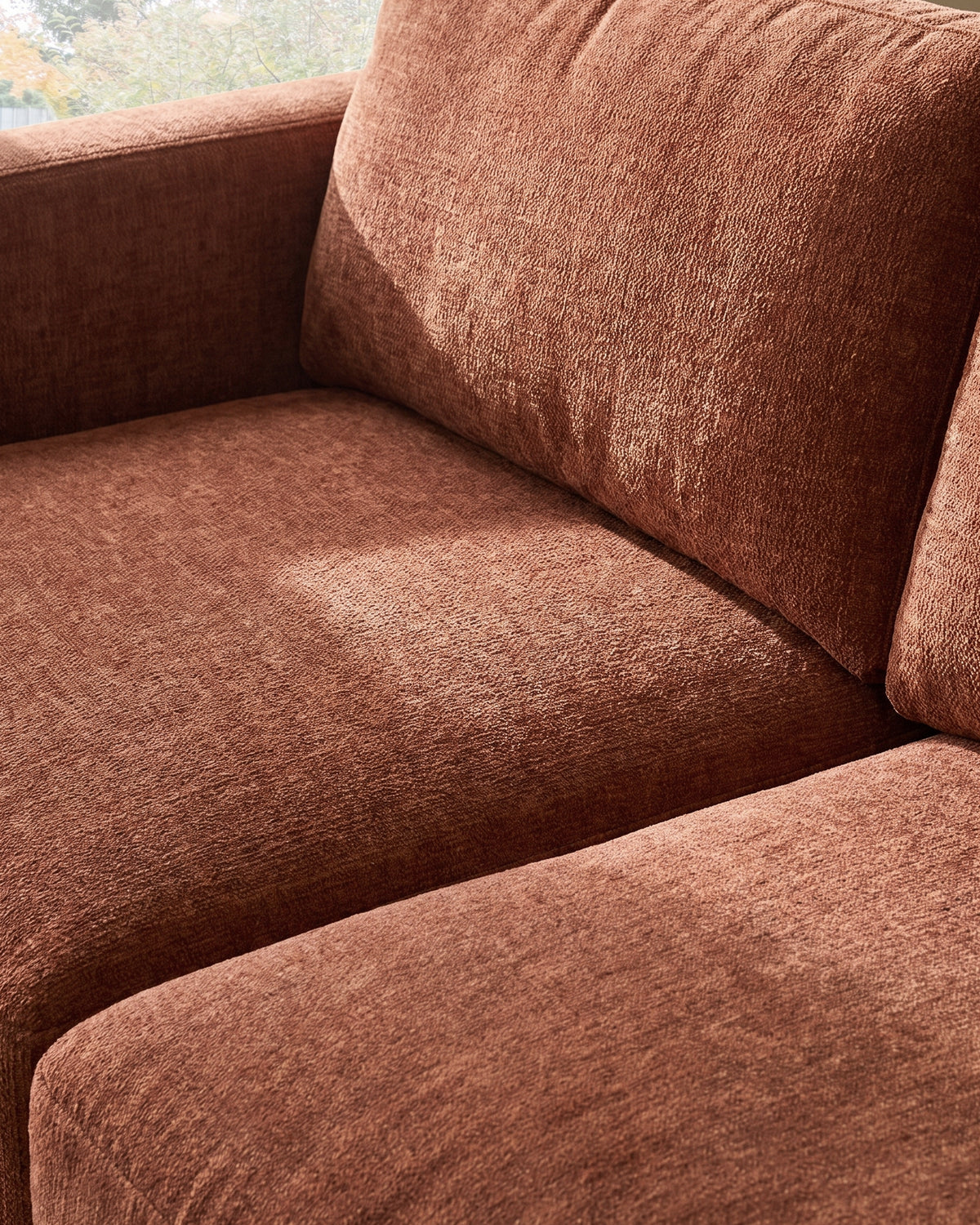 Eden 2-seater sofa in apricot fabric, close-up detail showing seat cushion and backrest texture.