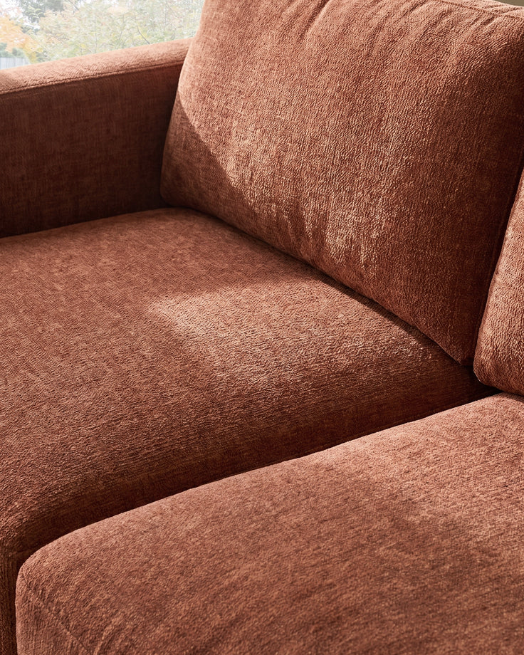 Eden 2-seater sofa in apricot fabric, close-up detail showing seat cushion and backrest texture.