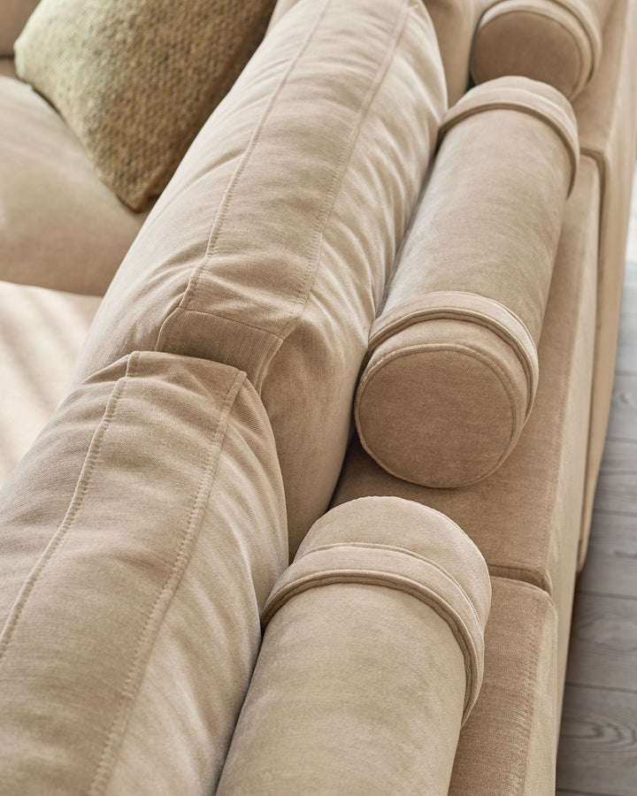 Eden 2-seater sofa in champagne fabric, close-up showing curved armrests and soft upholstery texture.